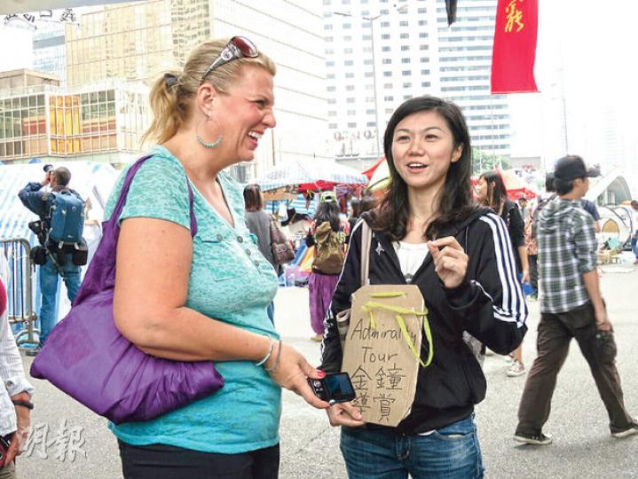 金鐘佔領區出現「金鐘導賞團」,義務導遊葉小姐(右)為外籍人士介紹佔區,佢話導賞團不定時提供服務,如果佢哋「開工」,就會持紙牌喺海富中心出現。(黎芷欣攝) 金鐘佔領區出現「金鐘導賞團」,義務導遊葉小姐(右)為外籍人士介紹佔區,佢話導賞團不定時提供服務,如果佢哋「開工」,就會持紙牌喺海富中心出現。(黎芷欣攝)