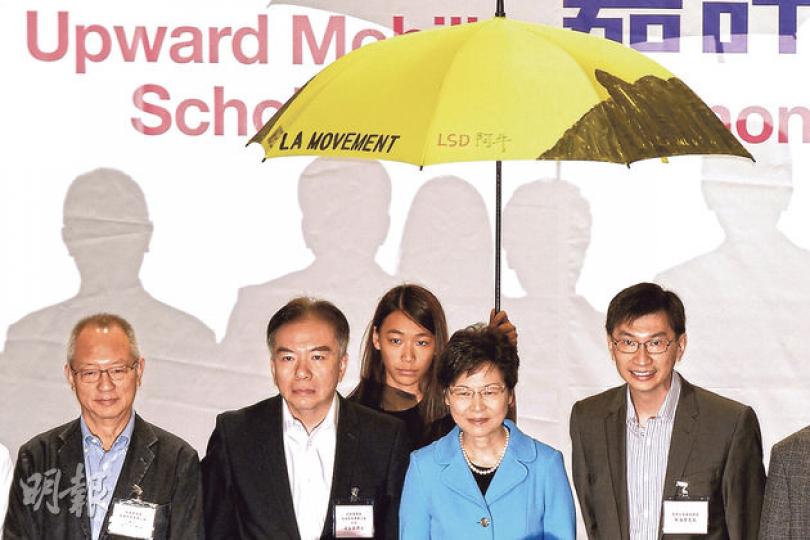政務司長林鄭月娥昨早出席2014年「明日之星——上游獎學金」嘉許禮,一名獲頒獎學金學生上台領獎拍照時,在林鄭月女娥後方舉起黃傘,以示支持佔領行動。(葉家豪攝) 政務司長林鄭月娥昨早出席2014年「明日之星——上游獎學金」嘉許禮,一名獲頒獎學金學生上台領獎拍照時,在林鄭月女娥後方舉起黃傘,以示支持佔領行動。(葉家豪攝)