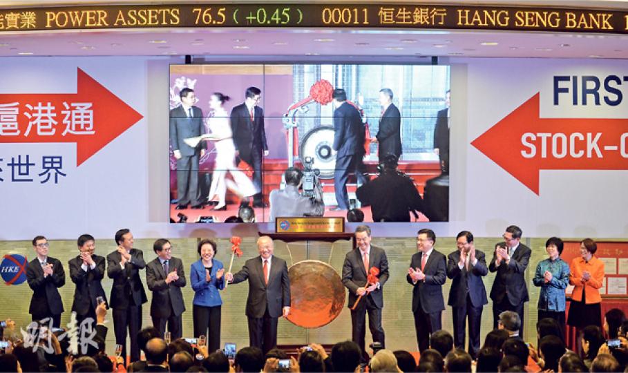 滬港通昨日在香港、上海兩地同時開通,香港由特首梁振英(右六)、港交所主席周松崗(右七)敲鑼,而圖中大屏幕直播的則是上海實况。交易第一天,滬股通與港股通吸金量南轅北轍,旺上海而不旺香港。(盧翊銘攝)為迎接滬港通首日開通,港交所昨日安排與上交所透過直播同步舉行開市儀式,香港方面由主席周松崗(中)及行政總裁李小加(右)主持。(盧翊銘攝)(明報製圖) 滬港通昨日在香港、上海兩地同時開通,香港由特首梁振英(右六)、港交所主席周松崗(右七)敲鑼,而圖中大屏幕直播的則是上海實况。交易第一天,滬股通與港股通吸金量南轅北轍,旺上海而不旺香港。(盧翊銘攝)為迎接滬港通首日開通,港交所昨日安排與上交所透過直播同步舉行開市儀式,香港方面由主席周松崗(中)及行政總裁李小加(右)主持。(盧翊銘攝)(明報製圖)