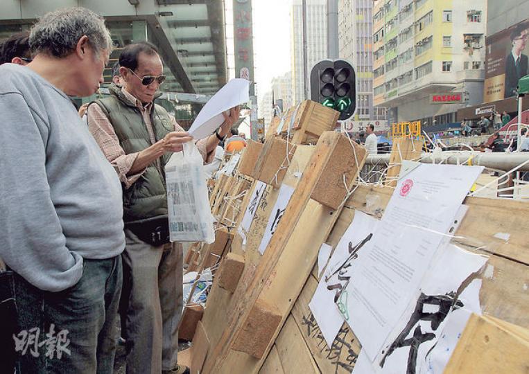 律師行職員昨午到旺角佔領區,於彌敦道與亞皆老街交界的路障張貼禁制令,但無宣讀內容,佔領人士無阻撓,有市民則拿起禁制令細閱。(李澤彤攝) 律師行職員昨午到旺角佔領區,於彌敦道與亞皆老街交界的路障張貼禁制令,但無宣讀內容,佔領人士無阻撓,有市民則拿起禁制令細閱。(李澤彤攝)