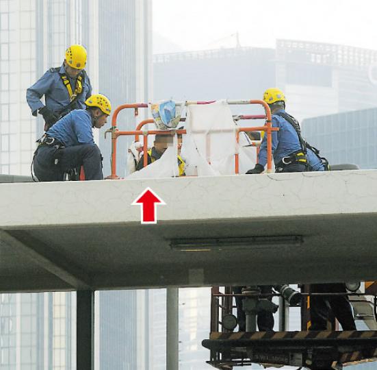 多次危坐高處「呼冤」的前法庭執達主任助理(箭嘴示),昨早再爬上灣仔告士打道一條行人天橋頂,消防員在旁展開游說。(鍾炳然攝) 多次危坐高處「呼冤」的前法庭執達主任助理(箭嘴示),昨早再爬上灣仔告士打道一條行人天橋頂,消防員在旁展開游說。(鍾炳然攝)