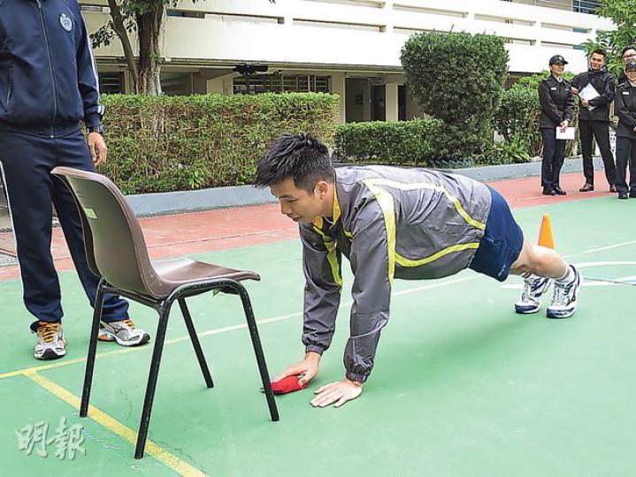 懲教主任、前港隊泳將殷浩俊示範其中一個體能測試項目俯撐取放,該項目要求投考者在地上俯撐期間,以其中一隻手從椅上取下豆袋,再交給另一隻手放上椅上,並重複整套動作。身形壯健的殷形容這項目十分辛苦,考驗臂力、腰力及協調。(黎芷欣攝) 懲教主任、前港隊泳將殷浩俊示範其中一個體能測試項目俯撐取放,該項目要求投考者在地上俯撐期間,以其中一隻手從椅上取下豆袋,再交給另一隻手放上椅上,並重複整套動作。身形壯健的殷形容這項目十分辛苦,考驗臂力、腰力及協調。(黎芷欣攝)