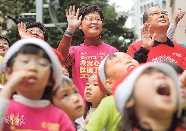 政務司長林鄭月娥（後排中）出席「聖誕頌歌節2014」開幕禮，同小朋友合照，令近日嚴肅嘅佢都變得特別輕鬆，佢仲推介人睇《爭氣》呢套電影。後排右為勞福局長張建宗。（盧翊銘攝）