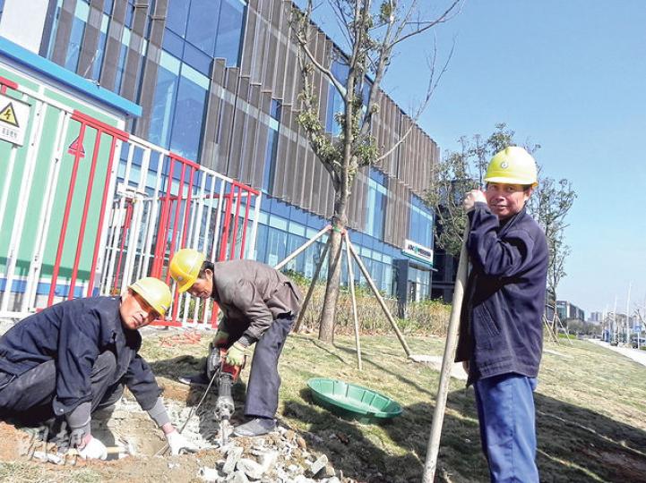 前海新區內的企業公館，部分企業已開始入駐，工人正忙於進行綠化收尾工作。（明報記者攝）