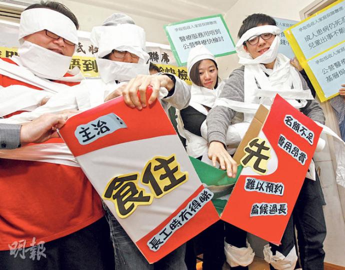 爭取低收入家庭保障聯席成員打爛寫有「食住先」字樣的道具,寓意打破現時公營門診服務的不足。(李紹昌攝) 爭取低收入家庭保障聯席成員打爛寫有「食住先」字樣的道具,寓意打破現時公營門診服務的不足。(李紹昌攝)