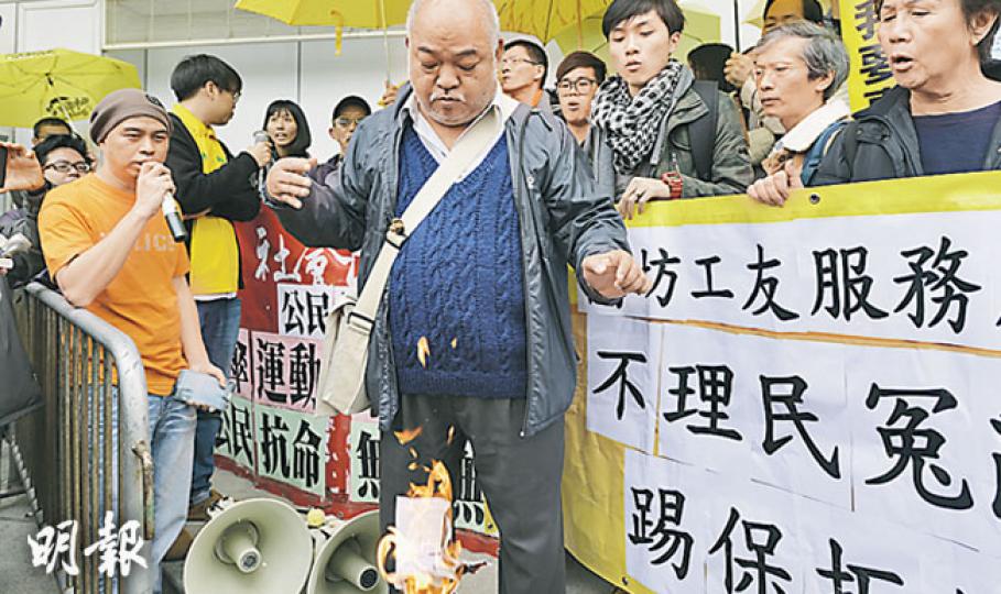 逾50名佔領期間被捕的人，昨到中區警署集體「踢保」，部分人舉起黃傘聲援，其中社民連成員「阿牛」曾健成（前中）在警署門外燃燒一張警方給他的報到通知書，以示不滿。（葉家豪攝）在佔領行動中三度被捕的九旬「黃伯」黃奮鋒，昨亦到中區警署「踢保」，並展示在警署內簽署的相關文件。（葉家豪攝）