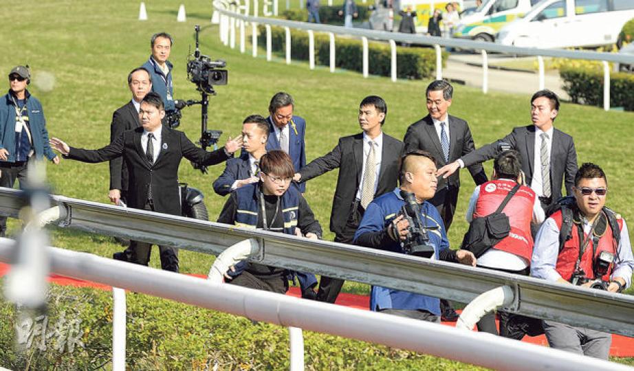 特首梁振英(後右二)昨在沙田馬場出席「130周年賽馬日」,負責第四場賽事的頒獎儀式。他在由跑道步向賽事終點的頒獎台期間,有人突從觀眾席擲蛋,但未有擲中他,梁全程保持微笑。後右四為賽馬會主席葉錫安。(余俊亮攝)有男子涉嫌向準備頒獎的特首梁振英擲蛋,未擲中梁但擲中馬會職員。事後觀眾席近跑道位置發現小量蛋殼。(余俊亮攝)涉嫌擲蛋男子(右)身穿深藍綠色外衣、戴有口罩,擲蛋後被保安人員制止及帶走。其後警員上前調查發現其背包藏約40隻雞蛋、萬用鉗及尼龍繩,以涉嫌普通襲擊、藏有工具可作非法用途等罪名拘捕。(余 特首梁振英(後右二)昨在沙田馬場出席「130周年賽馬日」,負責第四場賽事的頒獎儀式。他在由跑道步向賽事終點的頒獎台期間,有人突從觀眾席擲蛋,但未有擲中他,梁全程保持微笑。後右四為賽馬會主席葉錫安。(余俊亮攝)有男子涉嫌向準備頒獎的特首梁振英擲蛋,未擲中梁但擲中馬會職員。事後觀眾席近跑道位置發現小量蛋殼。(余俊亮攝)涉嫌擲蛋男子(右)身穿深藍綠色外衣、戴有口罩,擲蛋後被保安人員制止及帶走。其後警員上前調查發現其背包藏約40隻雞蛋、萬用鉗及尼龍繩,以涉嫌普通襲擊、藏有工具可作非法用途等罪名拘捕。(余
