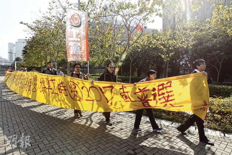 工黨昨日在政府總部門外拉起黃色長橫幅,向特首梁振英「追數」,包括就標準工時立法及要求2017年要有真普選。工黨已表明會否決政府提出的政改方案。(李紹昌攝) 工黨昨日在政府總部門外拉起黃色長橫幅,向特首梁振英「追數」,包括就標準工時立法及要求2017年要有真普選。工黨已表明會否決政府提出的政改方案。(李紹昌攝)