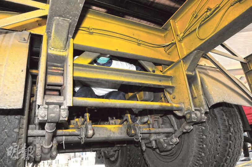 偷渡集團除教偷渡者如何匿藏貨櫃車拖架罅隙偷渡來港，更為越南人在港安排住宿及工作，提供「一條龍」服務，圖為入境處在車底放置假人（白衣）講解偷渡者匿藏位置。（鍾炳然攝）