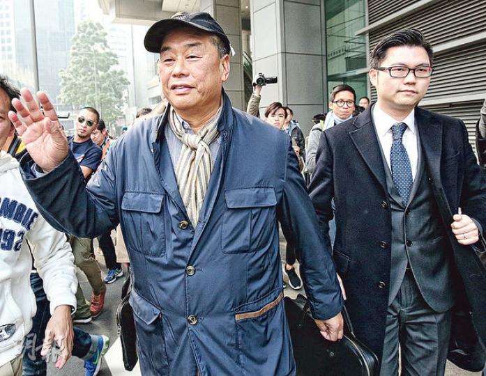 壹傳媒前主席黎智英（左）昨在兩名律師陪同下，到灣仔警總「預約被捕」，他被控組織及參與非法集結兩條罪名，其後「踢保」獲釋，但警方保留檢控權利。（李紹昌攝）民陣副召集人楊政賢（圖）昨午到灣仔警總「預約被捕」，獲10多名民陣成員聲援，最後「踢保」獲無條件釋放。圖為他進入警署前手持黃色紙傘留影。（葉家豪攝）