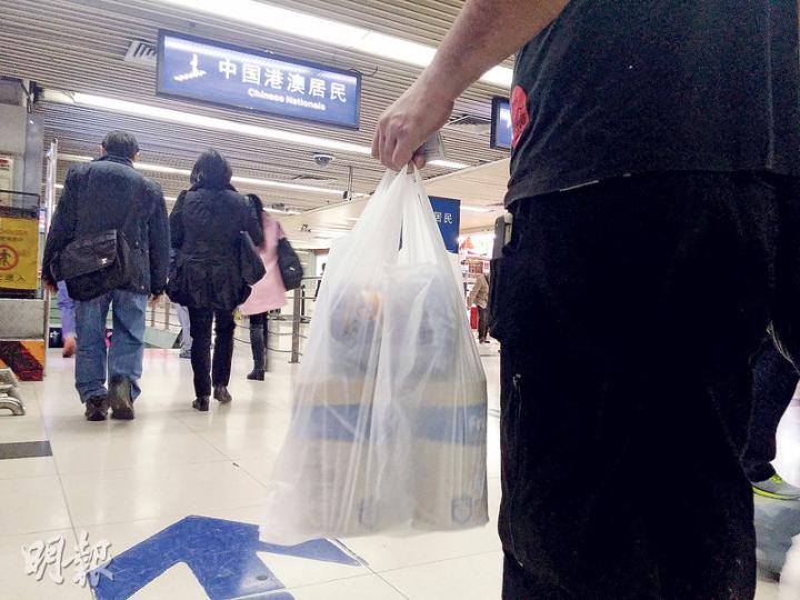本報記者昨帶「3罐」奶粉（兩罐未開封，一為空罐），品字形放在膠袋內（圖），經羅湖口岸過關，途經香港及內地海關檢查站時，均見有5至6名海關人員目視檢查，但未有截停搜查，順利過關。（明報記者攝）深圳羅湖口岸對出的通道，昨日未見如過往般有大量收購水貨奶粉者，通道亦泊有兩輛保安車輛。（明報記者攝）