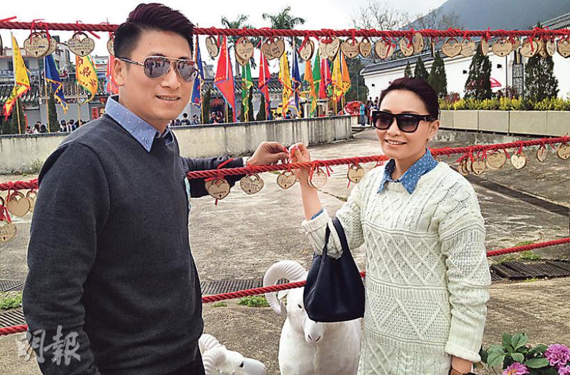 大埔林村今年新搞作,名為「誠心鎖願」,市民購買一對心形木牌後,寫低新年願望,再綁喺欄架嘅繩上。袁先生(左)喺木牌寫上「與女朋友永遠相愛」願望,右為其女友。(卓成家攝) 大埔林村今年新搞作,名為「誠心鎖願」,市民購買一對心形木牌後,寫低新年願望,再綁喺欄架嘅繩上。袁先生(左)喺木牌寫上「與女朋友永遠相愛」願望,右為其女友。(卓成家攝)