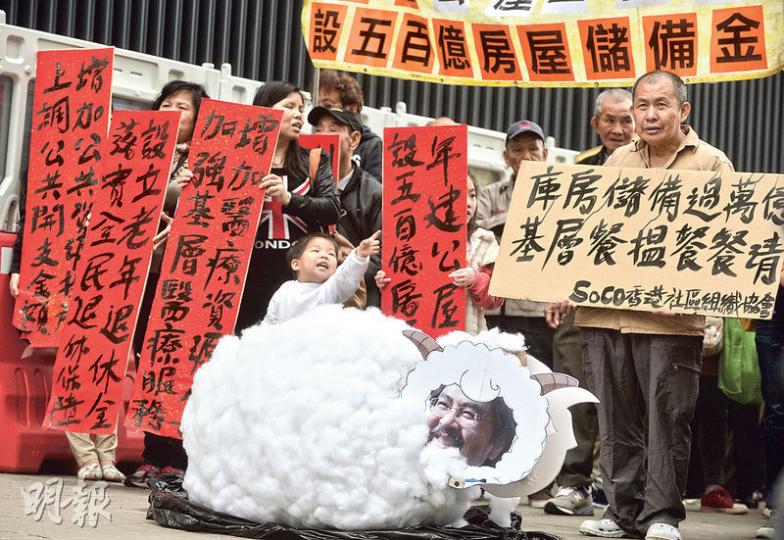 多個團體昨日先後到政府總部外請願,表達對財政預算案的期望,其中社區組織協會聯同居民請願,要求預算案還富於民,又製作「財爺綿羊」(前)作比喻,指庫房水浸、儲備逾1萬億元,但其實羊毛出自羊身上,要求政府與市民分享成果,包括設全民退保、500億元的房屋儲備金用作興建公屋等。(盧翊銘攝) 多個團體昨日先後到政府總部外請願,表達對財政預算案的期望,其中社區組織協會聯同居民請願,要求預算案還富於民,又製作「財爺綿羊」(前)作比喻,指庫房水浸、儲備逾1萬億元,但其實羊毛出自羊身上,要求政府與市民分享成果,包括設全民退保、500億元的房屋儲備金用作興建公屋等。(盧翊銘攝)