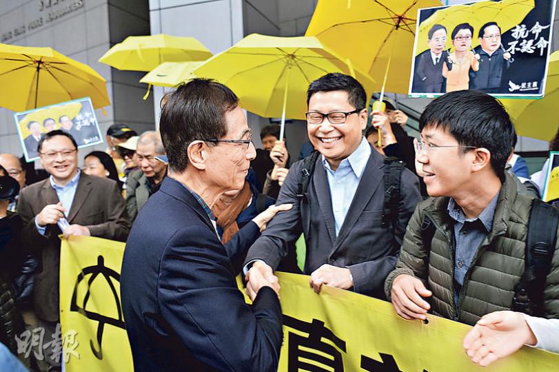 民主黨創黨主席李柱銘(背向鏡頭者)昨日亦有到警總接受「預約拘捕」,在場有約20名支持者舉起黃傘聲援,包括佔中發起人戴耀廷(左一)和陳健民(右二)。(葉家豪攝) 民主黨創黨主席李柱銘(背向鏡頭者)昨日亦有到警總接受「預約拘捕」,在場有約20名支持者舉起黃傘聲援,包括佔中發起人戴耀廷(左一)和陳健民(右二)。(葉家豪攝)