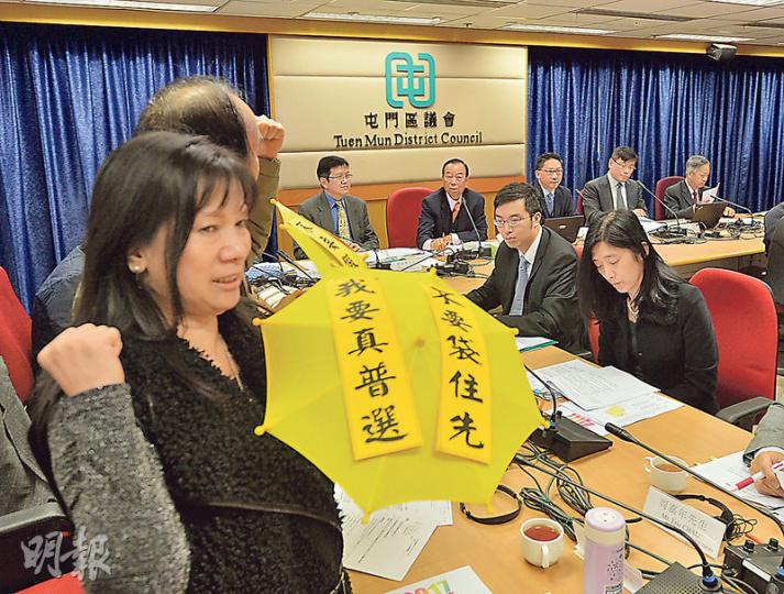 律政司長袁國強(後排右三)昨日到屯門區議會諮詢政改方案,當區區議員何俊仁及泛民成員於司長發言前舉黃傘,並離場抗議。(鄧宗弘攝)民建聯屯門區議員陳文華(中)在區議會主席劉皇發(左)與律政司長袁國強(右)背後舉牌,表達支持《基本法》與人大8•31決定。(鄧宗弘攝) 律政司長袁國強(後排右三)昨日到屯門區議會諮詢政改方案,當區區議員何俊仁及泛民成員於司長發言前舉黃傘,並離場抗議。(鄧宗弘攝)民建聯屯門區議員陳文華(中)在區議會主席劉皇發(左)與律政司長袁國強(右)背後舉牌,表達支持《基本法》與人大8•31決定。(鄧宗弘攝)