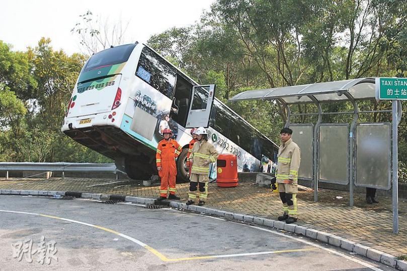大嶼山旅遊巴衝300米撞毁路邊鐵欄後，車尾翹起擱路邊石壆，司機乘客由消防協助從太平門逃出車廂。（伍浦鋒攝）意外中旅遊巴因大樹阻擋，未致直衝落山坡。（伍浦鋒攝）