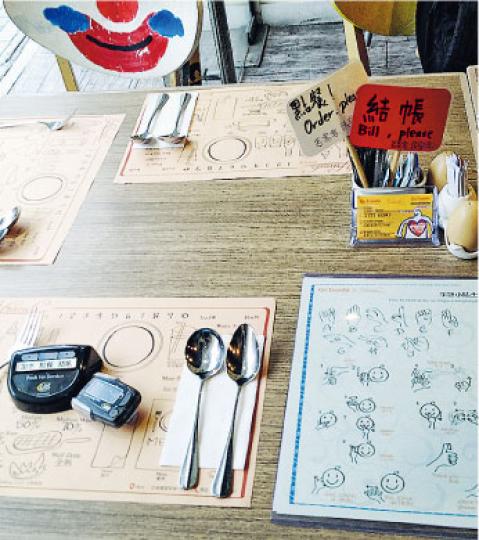 客人來到聾人意式餐廳「有情有意（Friends）」可選擇透過揮動餐桌上的紅旗白旗表示結帳、點餐，或可透過點菜機要求加水、點餐、結帳，甚至可即場學習簡單手語或指指餐廳提供的餐桌紙與聾人侍應溝通。（卓成家攝）