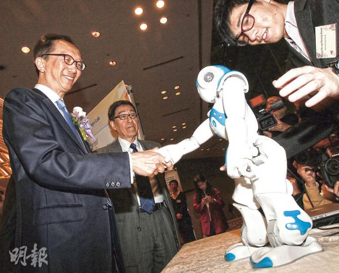 前財政司長梁錦松（左）昨出席城市大學僱主午宴，並參觀學生作品。有學生用自己設計的手機程式，操控機械人與梁錦松握手。（李紹昌攝）