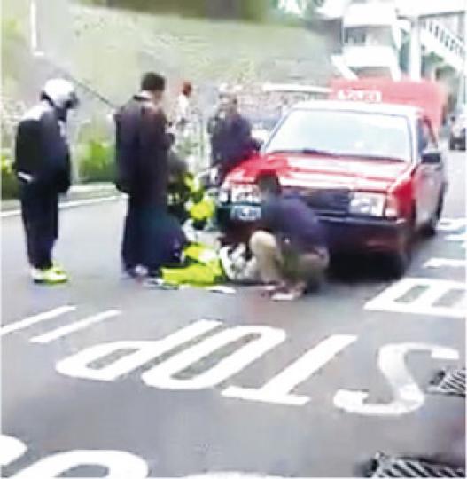 車禍中，交通警員的右手掌被壓於的士前輪受傷被困，其間司機以「車唧」升起的士拯救，附近熱心人士亦協助救援。（網民thai love攝）