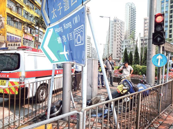 被撞電單車剷上安全島（圖），掃毁鐵欄、燈箱及路牌等，兩人均飛出車外。（賴俊傑攝）