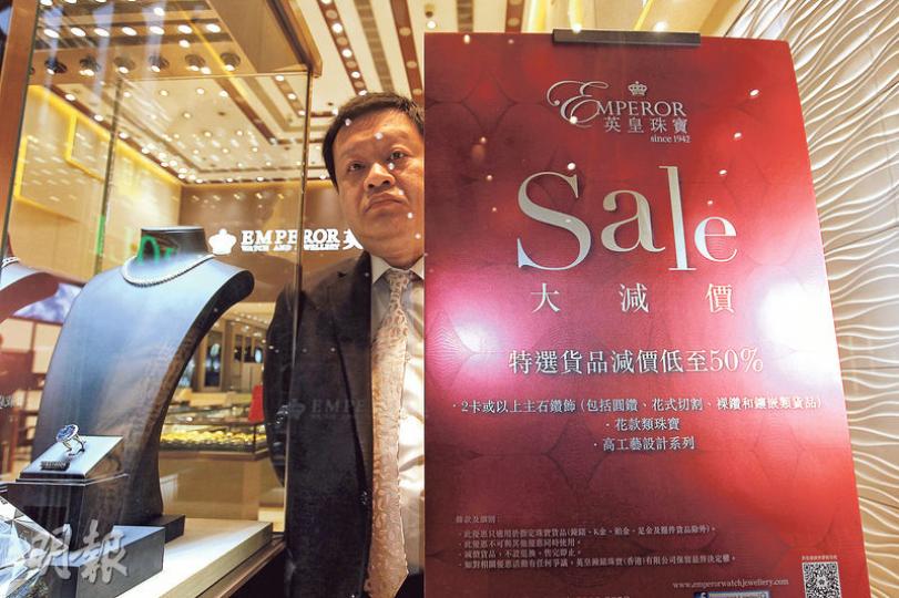 圖為英皇鐘錶珠寶在中環皇后大道中門市，當眼處擺出標榜貨品減價五折的紙牌；但記者昨日所見，兩小時內只有3至4名客人出入（下圖）。（郭慶輝攝）英皇鐘錶珠寶劈價四至六成，主要為旗下自家品牌大幅減價，圖為店內減價鑽戒。（鄭智文攝）