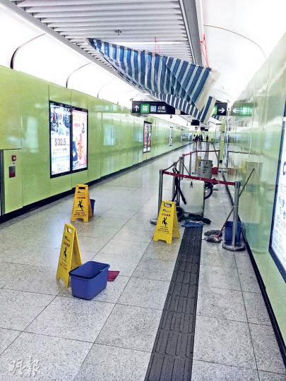 港鐵港大站一行人通道漏水，港鐵在假天花吊帆布，將水引至地下兩個大桶，漏出的水一度形成水柱，盛了約四分一個大水桶。（張煒明攝）