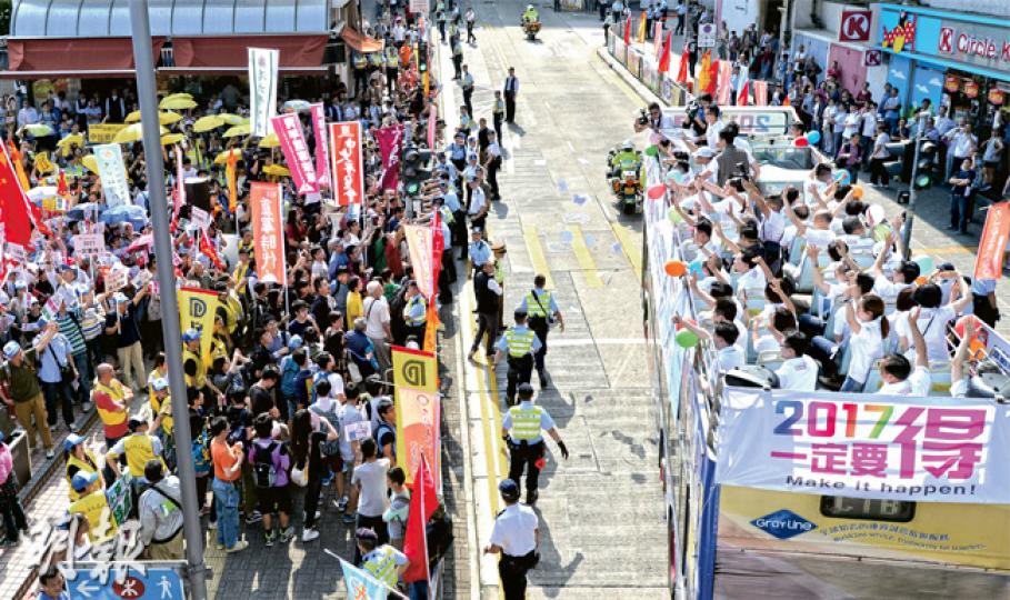 政務司長林鄭月娥昨率領30多名官員登上開篷巴士巡遊港九新界多區,「嗌咪」宣傳政改方案,不過全程官員沒有落車。在其中一站的樂富中心外,巴士到達時直接駛過,官員向行人路旁等候多時的支持政改市民揮手,但無接觸,反對政改的示威者則舉起黃傘,在警察阻擋下示威。(余俊亮攝)學聯及多間大專院校學生、人民力量與社民連共約20多名代表,昨在堅尼地城高舉黃傘和「我要真普選」標語,反對「袋住先」,同場有30多名支持政府人士。大批警員在場維持秩序,分隔兩批人。官員只在巴士上向途人揮手,未有落車。(李紹昌攝)多個建制團體 政務司長林鄭月娥昨率領30多名官員登上開篷巴士巡遊港九新界多區,「嗌咪」宣傳政改方案,不過全程官員沒有落車。在其中一站的樂富中心外,巴士到達時直接駛過,官員向行人路旁等候多時的支持政改市民揮手,但無接觸,反對政改的示威者則舉起黃傘,在警察阻擋下示威。(余俊亮攝)學聯及多間大專院校學生、人民力量與社民連共約20多名代表,昨在堅尼地城高舉黃傘和「我要真普選」標語,反對「袋住先」,同場有30多名支持政府人士。大批警員在場維持秩序,分隔兩批人。官員只在巴士上向途人揮手,未有落車。(李紹昌攝)多個建制團體