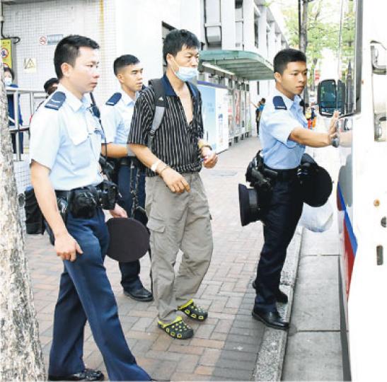 曾參與八九民運的內地人王登耀(中)前晚在旺角參與「鳩嗚」被捕,昨日由警員押解到廣華醫院求診後,再押上警車離開,其間他被警員用「解犯鏈」鎖起雙腕。(鍾炳然攝) 曾參與八九民運的內地人王登耀(中)前晚在旺角參與「鳩嗚」被捕,昨日由警員押解到廣華醫院求診後,再押上警車離開,其間他被警員用「解犯鏈」鎖起雙腕。(鍾炳然攝)