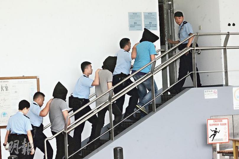 3名涉嫌在香港迪士尼樂園外兜售「賊贓門票」被捕的疑犯,由警員黑布蒙頭押返警署扣查。(伍浦鋒攝) 3名涉嫌在香港迪士尼樂園外兜售「賊贓門票」被捕的疑犯,由警員黑布蒙頭押返警署扣查。(伍浦鋒攝)