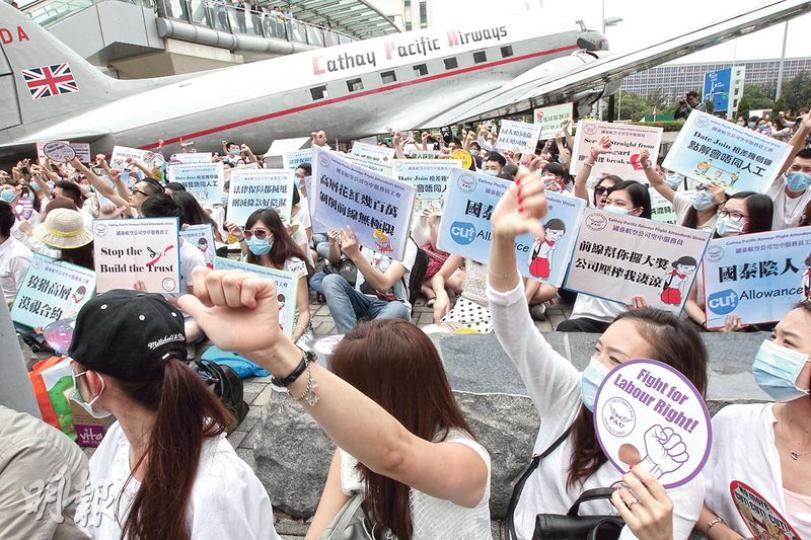 國泰空中服務員工會昨日發起升級行動,不少人響應呼籲穿上白衣及帶同黑傘,在國泰城外靜坐及圍繞國泰城遊行一圈表達訴求,有員工形容行動是「5月圍城」。(李紹昌攝) 國泰空中服務員工會昨日發起升級行動,不少人響應呼籲穿上白衣及帶同黑傘,在國泰城外靜坐及圍繞國泰城遊行一圈表達訴求,有員工形容行動是「5月圍城」。(李紹昌攝)