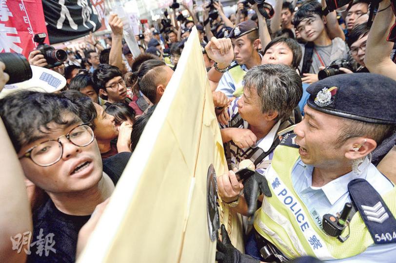 支聯會昨午舉行六四論壇，數名本土力量成員（包括中間綠衣者）「踩場」抗議，要求支聯會解釋如何建設民主中國等，令論壇一度中斷。部分市民要求抗議者離開，雙方推撞，情况混亂，及後警員介入，把兩批人分隔。（郭慶輝攝）

