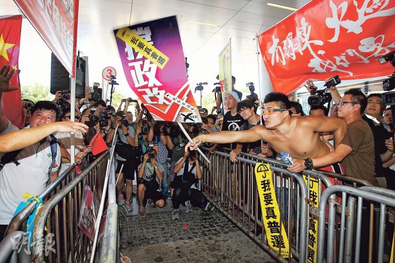 廣西社團總會成員（左）及反對政改陣營（右方）於立法會示威區集會，中間雖有鐵馬分隔，但兩方口角不斷，不時有人擲物，兩方糾察均拉開對罵者，未見有嚴重肢體衝突。（李紹昌攝）逾200名穿著印上順序號碼白衣的撐政改人士參與集會，記者多番問他們所屬組織及集會目的，但沒有人願意回應。（林俊源攝）昨午逾50名健碩大漢穿同款靴及腰包，頭戴印有「73」的同款帽，部分人戴口罩、有硬墊的手套或持對講機，於示威區及添馬公園整齊排列。（鄧宗弘攝）