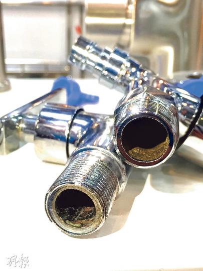 深圳一建材店職員向記者展示兩款分別是合成金製水龍頭（左）及銅製水龍頭（右），前者喉管已有氧化迹象，店員直言其水不宜飲用。（林俊源攝）
