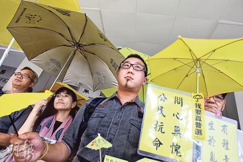 歐陽東（圖）在立法會議員馮檢基等伴隨下步出法院，撐起黃傘高呼口號。他稱身為藝術家面對社會議題，或會犧牲性命或挑戰法律灰色地帶，站出來抗命。（李紹昌攝）