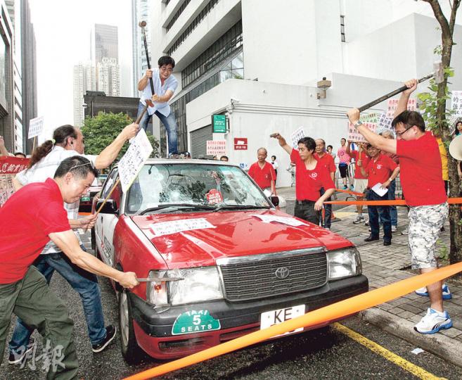30多名的士業界代表昨示威，促當局全面取締白牌車，並以鐵槌打爛的士表達不滿。（李紹昌攝）
