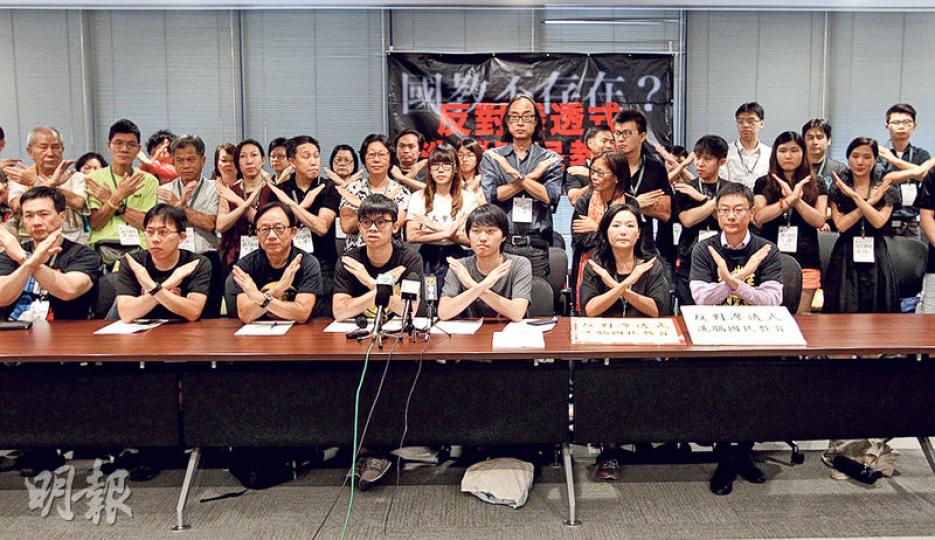 36個民間團體聯署反對教育局今年4月出版的基本法教材，指教材偏頗且滲入國民教育元素。圖為參與團體成員擺出2013年反對德育及國民教育科時的手勢。（林俊源攝）