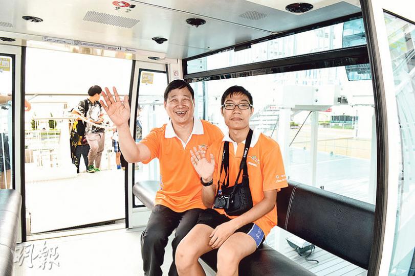 香港傷健共融網絡有限公司主席莫儉榮（前左）及兒子莫早謙（右）將一齊參加街馬活動，昨日練跑後一齊乘坐中環摩天輪。（陳淑安攝）
