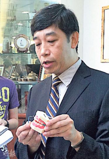 港大牙醫學院牙科公共衛生講座教授盧展民以牙齒模型展示氟化銀溶液治療過程。（劉琪琦攝）