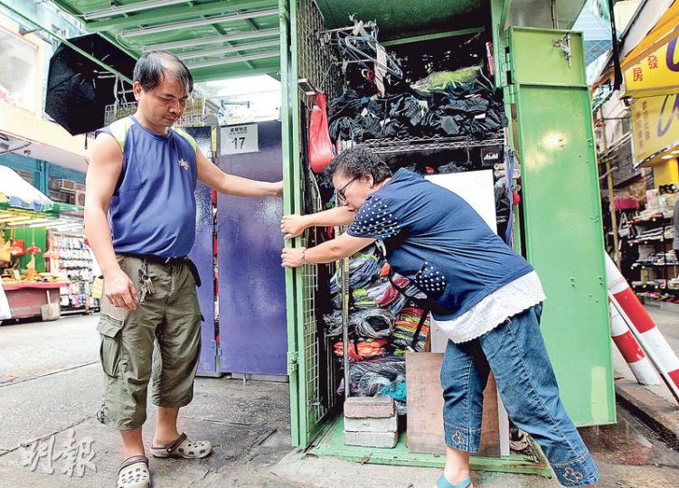 花園街排檔檔主潘太（右）與助手合力才能「收檔」，她指裝修手工大有問題，接口位不整齊，食環署亦指物料厚度不合規格，她要求承辦商退回訂金。（李澤彤攝）