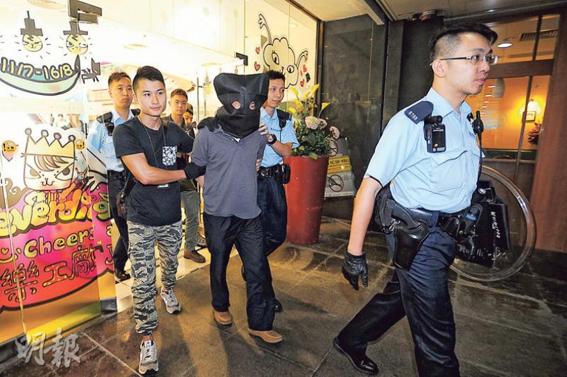 疑因欠債鋌而走險打劫銀行的被捕疑犯，由警員黑布蒙頭押返警署扣查。（衛永康攝）警方展示疑犯犯案時所攜的背囊、兩把刀及打火機等證物。（衛永康攝）