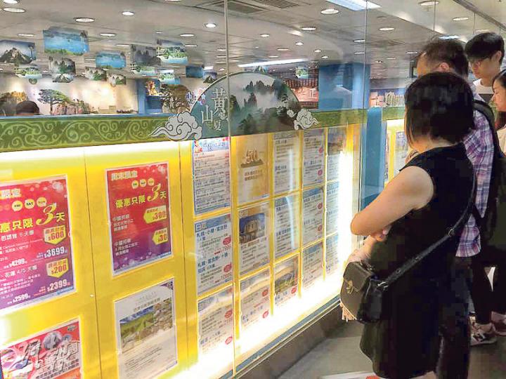 政府昨日取消對韓國的紅色外遊警示，有旅行社推出低至2000多元優惠團，不少市民駐足門外看相關宣傳單張。（沈燕媚攝）