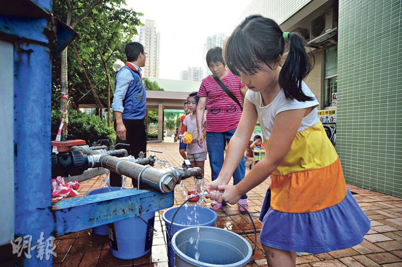 政府驗出馬鞍山欣安邨食水含鉛量超標，昨日安排水箱及水車向邨民派水，亦有工程人員將邨外食水管臨時駁入屋邨。圖為一名女孩用水桶載水回家。（蘇智鑫攝）