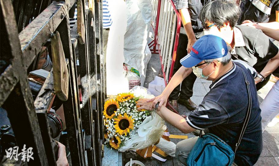 19歲死者陳詠釿的父親（前）帶着一束太陽花到場，其間撫摸花束，低語「快啲返嚟呀，傻豬仔」，淚如泉湧的他由妻子（後）安慰。（林俊源攝）