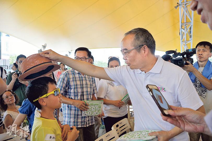 民政局長劉江華（右）出席沙田區清潔香港嘉年華暨頒獎典禮時，只係向街坊派發清潔包，見到小朋友戴草帽，仲好好奇咁睇
