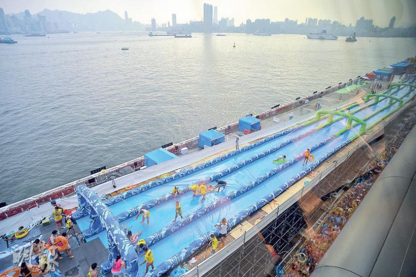 一連3日在啟德郵輪碼頭舉行的Slide the City前天開幕，昨日參加者仍多，在滑水梯中常有碰撞，但無損參加者興致，稱「炒埋一碟先好玩」。（蘇智鑫攝）昨晨的參加者一般需排隊等候15至45分鐘，至中午入場者漸多，至下午已見長龍（圖），約需排隊等候1至2小時才能滑一次。（蘇智鑫攝）