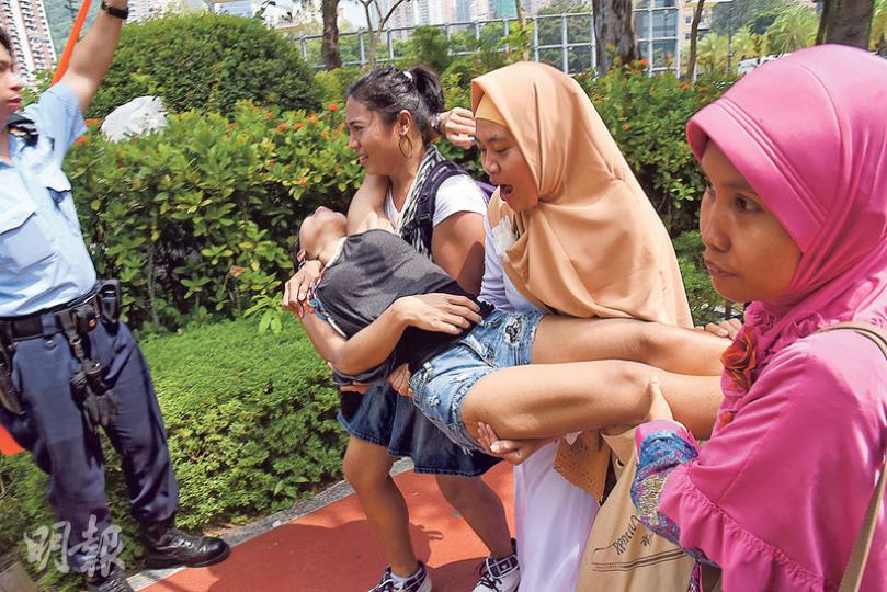 一名印尼人疑似中暑昏迷，由友人合力抬起移往陰涼地方，沿途更大叫「幫手呀、幫手呀」。（林智傑攝）
