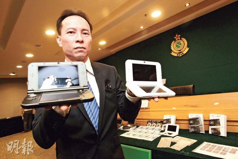 海關版權及商標科技罪案調查組指揮官方永佳在記者會上，分別講述破案經過及展示檢獲的電子遊戲產品。（李紹昌攝）涉案店舖是在網上下載正版遊戲的破解版儲入記憶卡（左圖黑色卡）後，再插入規避器（左圖白色卡），然後將規避器插入手提電子遊戲機，令遊戲機系統誤認是正版遊戲。右圖為正版遊戲卡。（李紹昌攝）