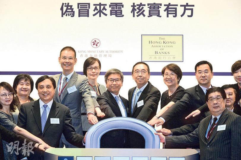 金管局、銀行公會等合作，提高市民對偽冒銀行來電的防範意識，昨舉辦宣傳活動，金管局副總裁阮國恒（左四）認為，市民對防範電話騙案意識不足，冀21間銀行設立熱線後，有助核實聲稱銀行職員的來電者真偽。左五為銀行公會署理主席梁兆基。（蘇智鑫攝）