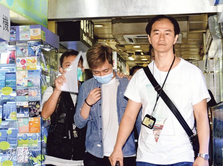 先達廣場有店舖疑將翻新iPhone 6當新機出售，海關人員昨在蘋果公司人員陪同下即場檢驗手機，拘捕一名涉案店員（中）。（賴俊傑攝） 海關人員檢走6部懷疑被翻新後當新機出售的iPhone 6。（賴俊傑攝）