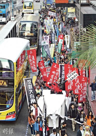 昨日的元旦遊行主辦者稱有近4000人參與，警方則稱高峰時有約1600人。遊行者沿途高叫「反對大白象」、「力爭全民退保」、「梁振英下台」等口號。帶頭者帶同一隻2米高的紙製「大白象」，代表不要大白象工程。（李紹昌攝）政府公布任命李國章為港大校委會主席，昨日不少遊行者表達不滿，其中有來自學聯的遊行者持「踢走李國章」、「不要梁粉治校」等標語。（鍾林枝攝）